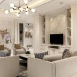 Elegant modern living room with cream-toned sofas, marble accents, and ambient lighting.